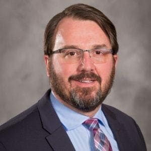 a man with glasses and a beard wearing a suit and tie